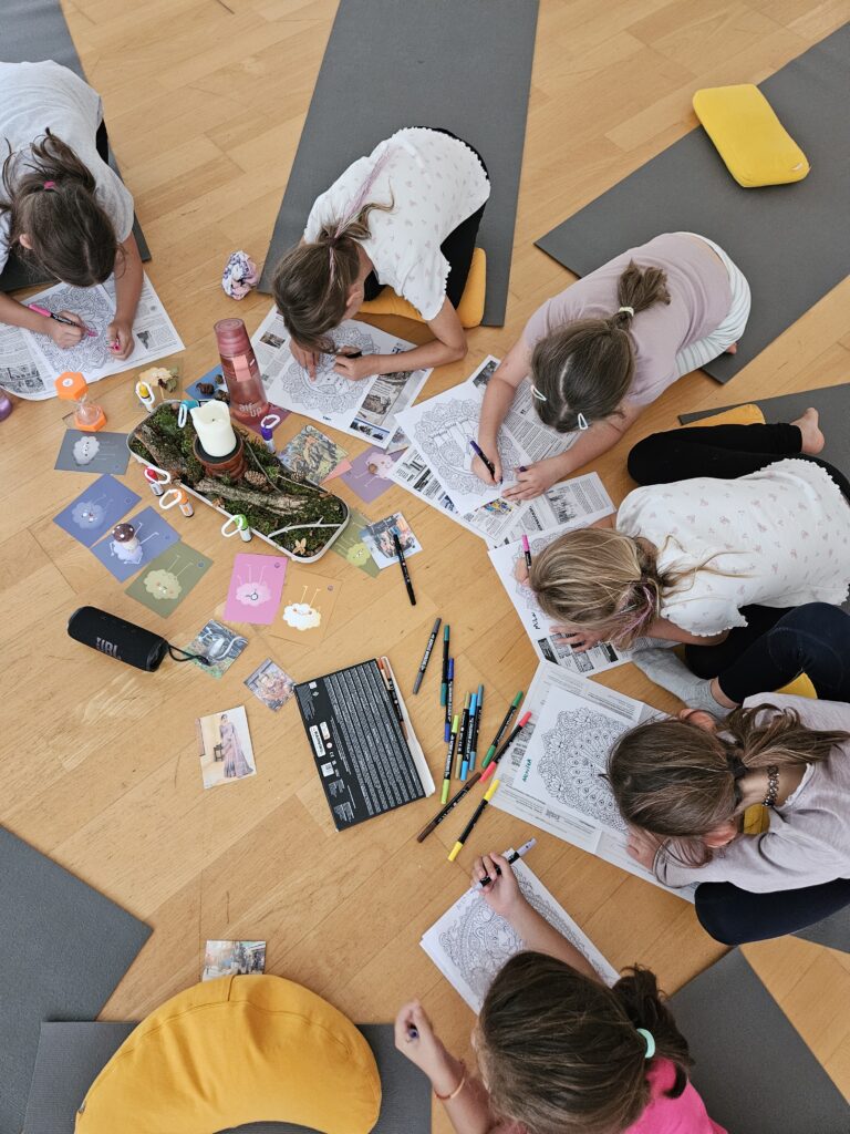 Kinder malen Mandalas in der Entspannungsphase beim Kinderyoga in Ebringen, in der Mitte Kerze und Yogakarten