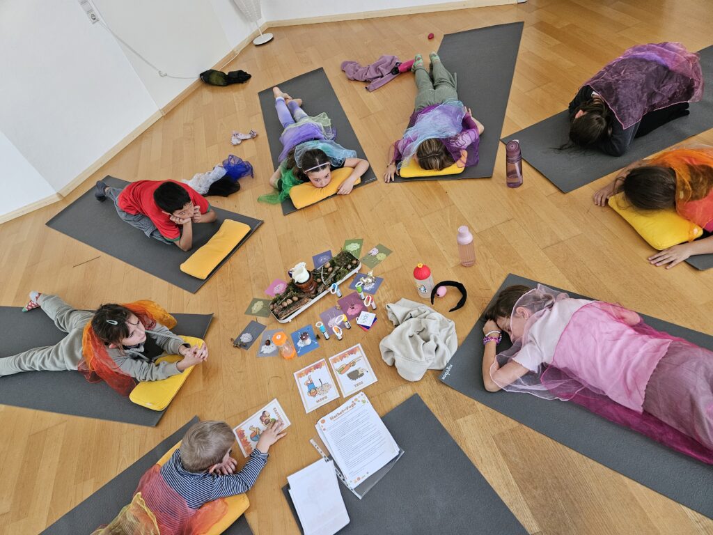 Kinderyoga in Ebringen bei Freiburg: Kinder liegen auf ihren Matten im Kreis um eine Yoga-Geschichte